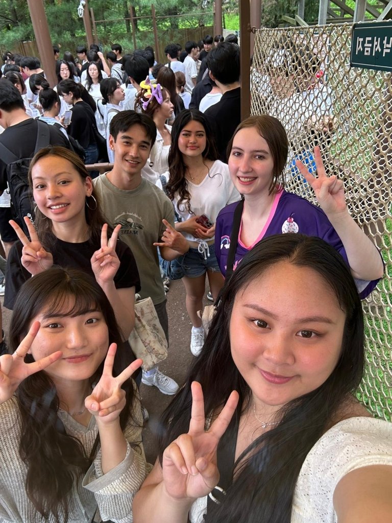 Students smile and make peace signs at the camera in the midst of a huge crowd outside