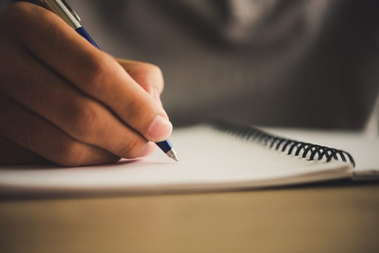 Hand writing with a pen in an open notebook