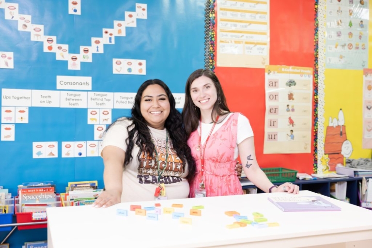 Two education students stand in an elementary school classroom