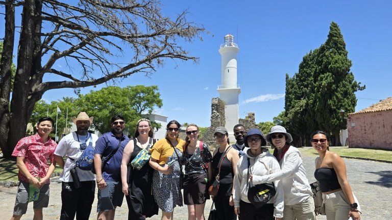 Students and faculty posing in front of statue