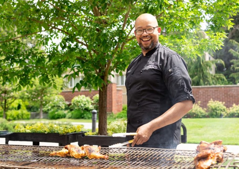 A Bon Appetit cook smiles while working at a grill outside