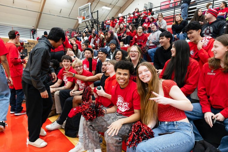 Students in red shirts pack the stands at a basketball game