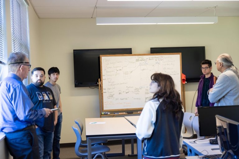 A team of students speaks with judges about their project
