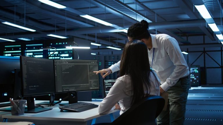 Two people look at a computer screen in an office