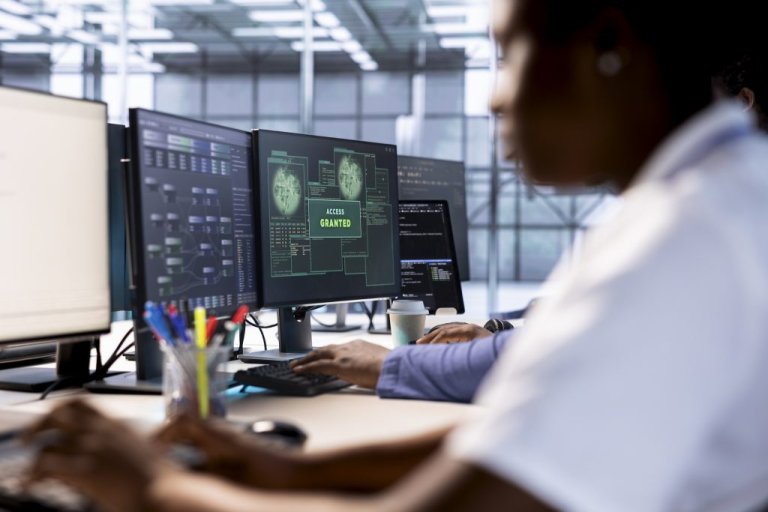 A person works at a series of computer screens