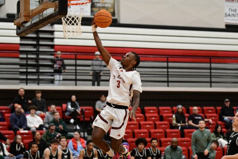 A Saints basketball player jumps to dunk a basketball in a hoop