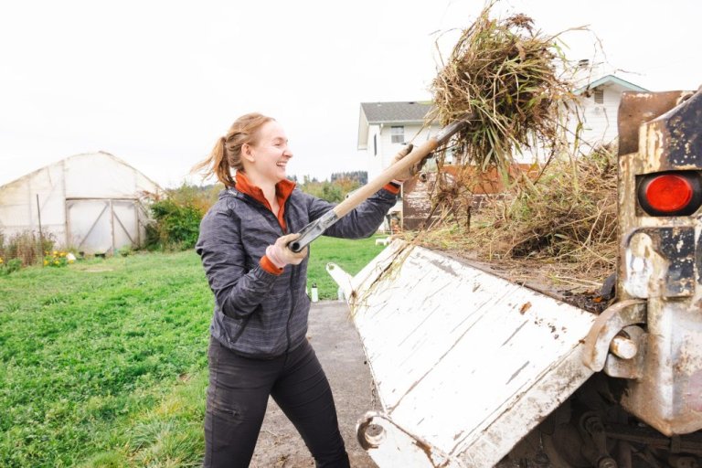 A volunteer loads a pitchfork of grass into a truck bed
