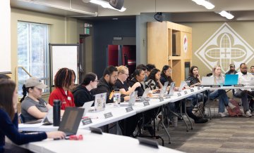 ASSMU students sit at conference tables in a meeting
